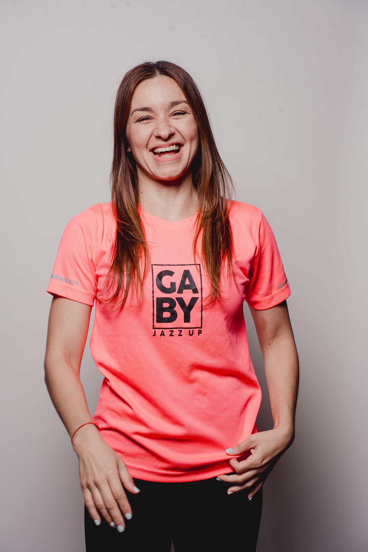 Mujer riendo, con una camiseta rosa brillante con el logo 
