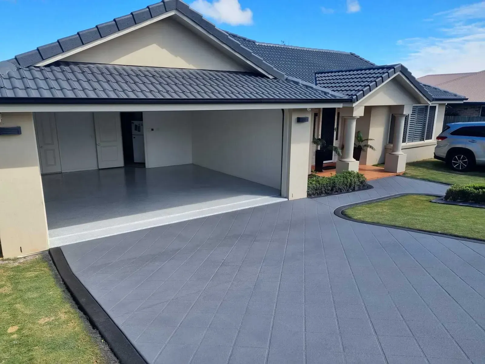 Exterior of a Beige House With a Grey Driveway and Garage — SRS Concreting In Glenvale, QLD