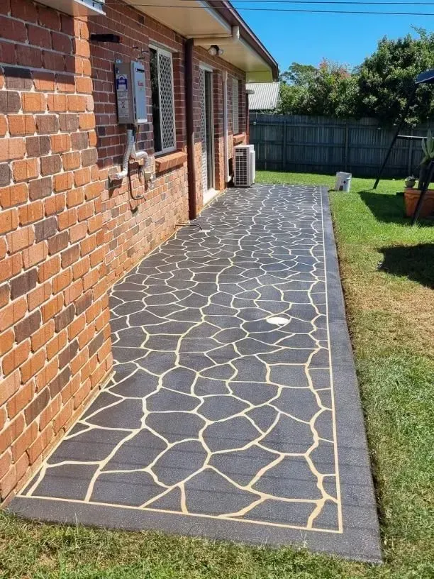 Brick Home With Dark Grey Patio, Beige Border, and Natural Stone Pattern — SRS Concreting In Crows Nest, QLD