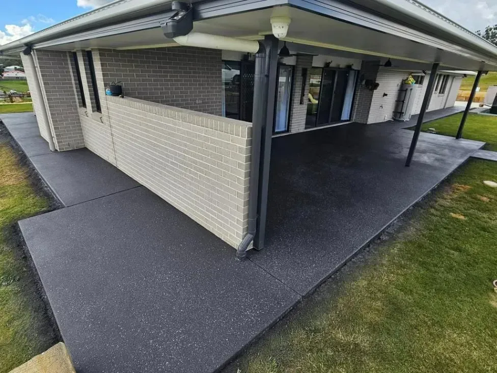 Dark Grey Concrete Patio Next to a Brick House With a Covered Porch — SRS Concreting In Dalby, QLD
