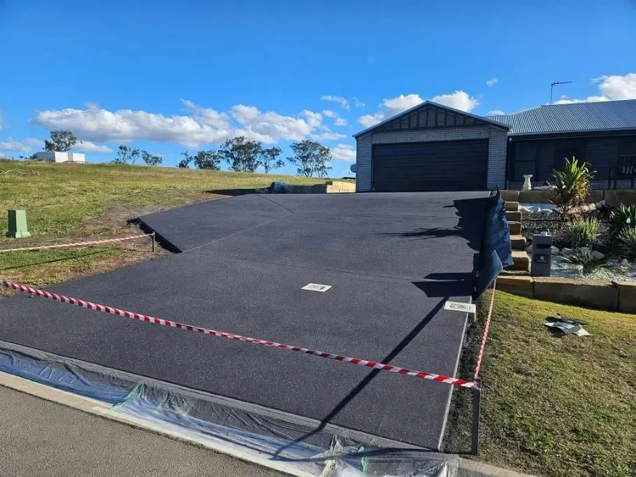 Newly Paved Asphalt Driveway Leading to a House With a Garage — SRS Concreting In Gatton, QLD