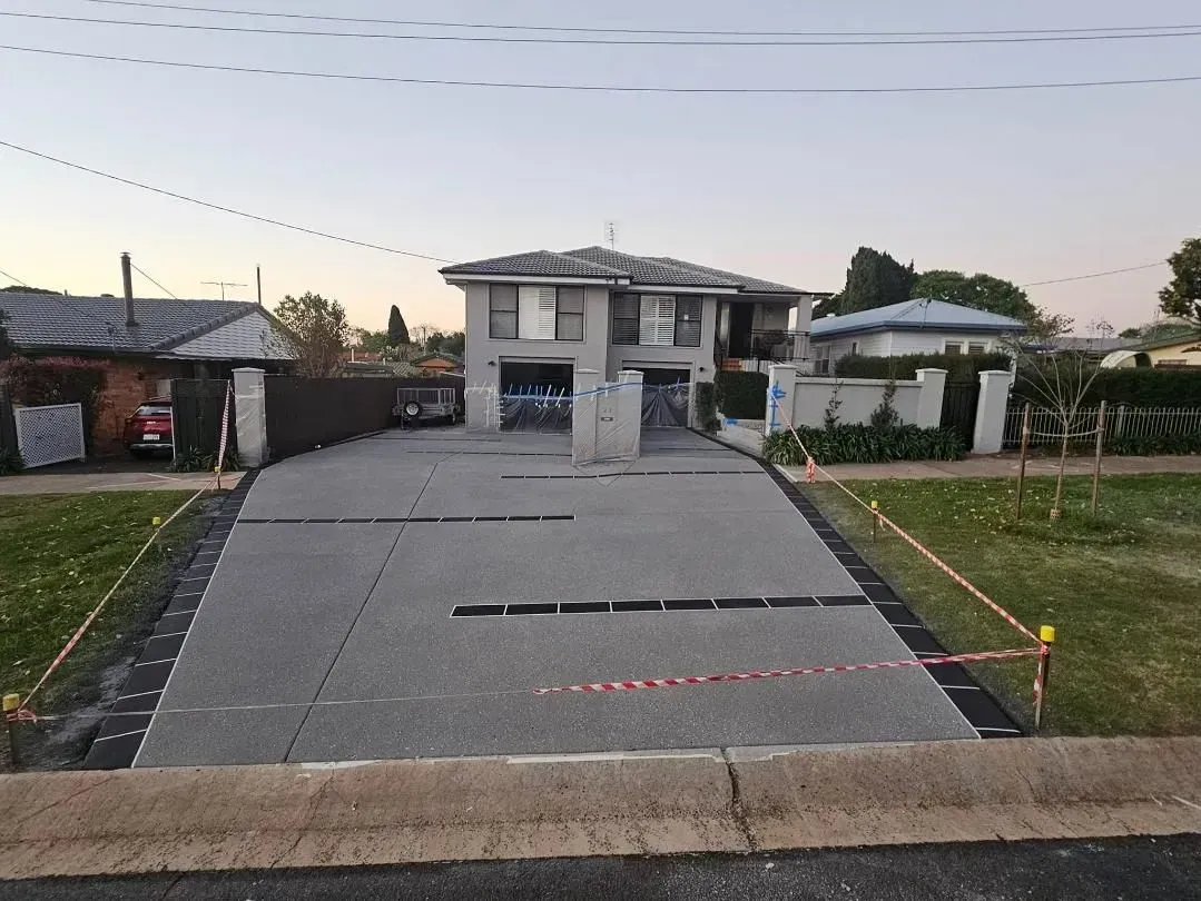 Newly Paved Driveway in Front of a Two-story House, With Safety Barriers in Place — SRS Concreting In Pittsworth, QLD