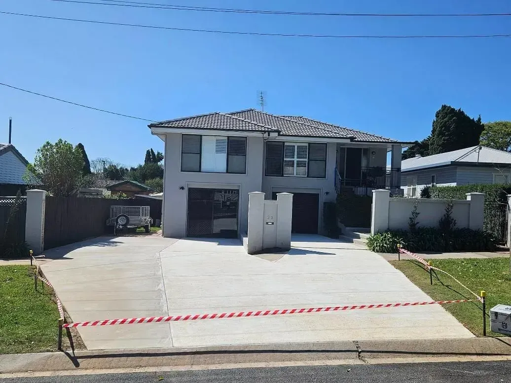 Two-story House With Grey Stucco Exterior, Driveway, and Red and White Caution Tape Across the Entrance — SRS Concreting In Pittsworth, QLD