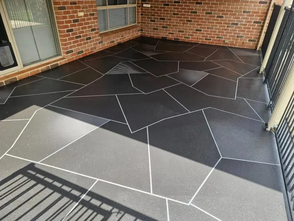 Black Patio With White Grout Lines, Next to a Brick Wall and Railings — SRS Concreting In Highfields, QLD