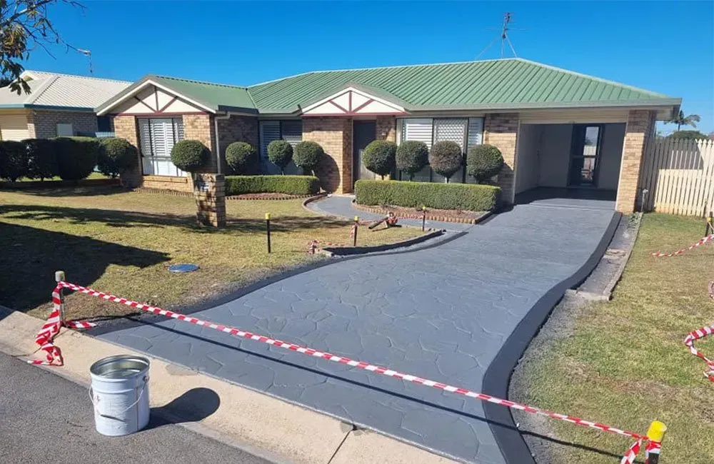 House With Grey Driveway, Green Roof, and Manicured Landscaping — SRS Concreting In Glenvale, QLD