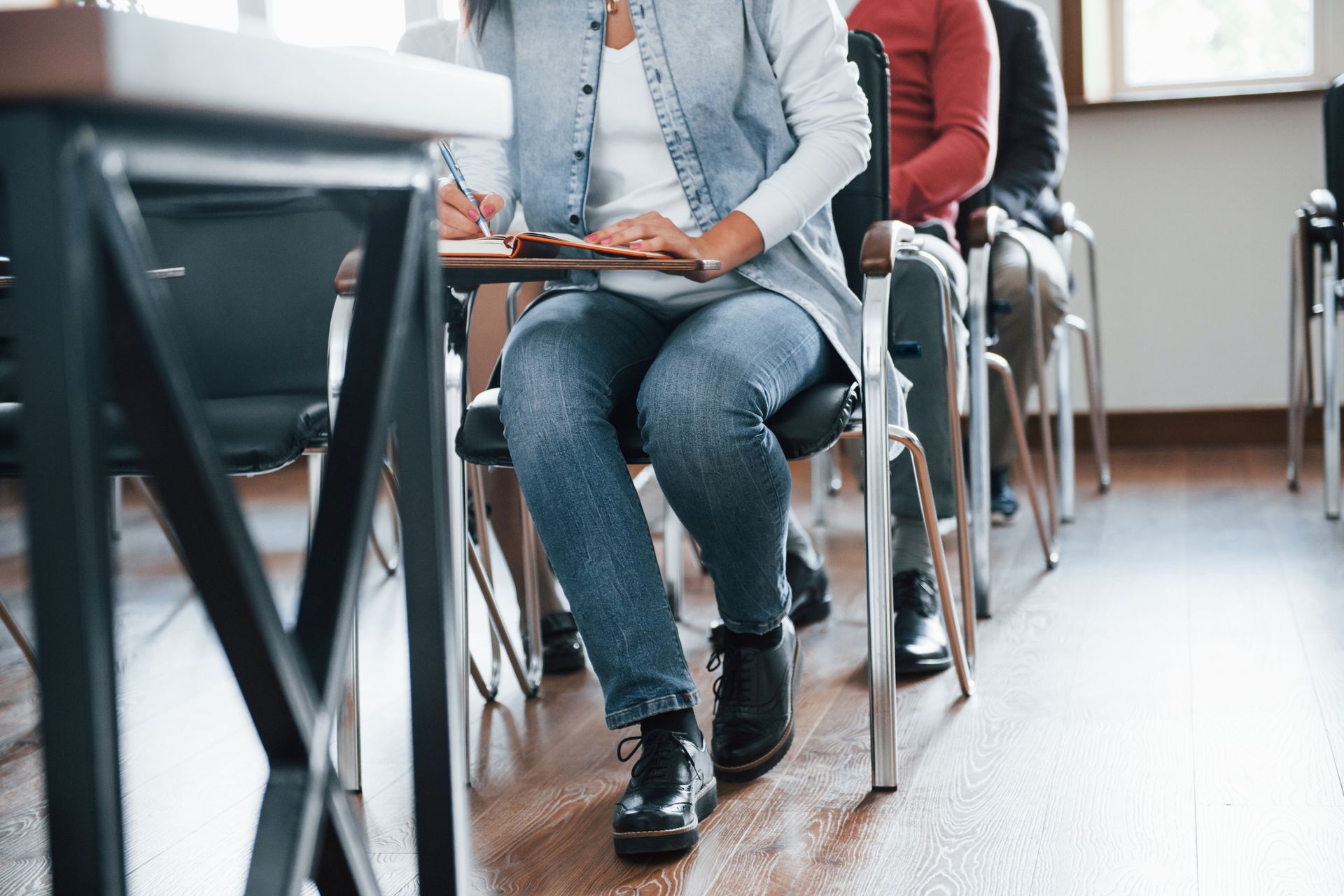 A group of people are sitting at desks in a classroom.