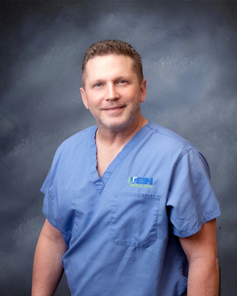 A man in a blue scrub is smiling for the camera