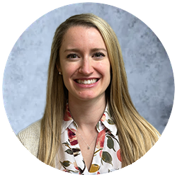 A man in a blue scrub top is smiling for the camera