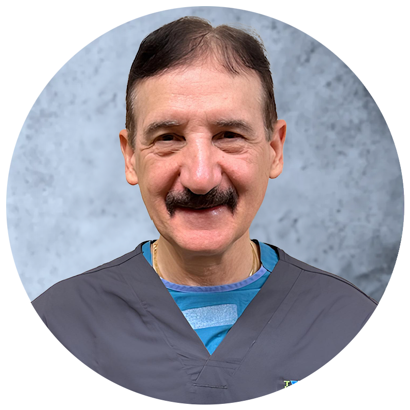 A man with a mustache is wearing a scrub top and smiling for the camera.