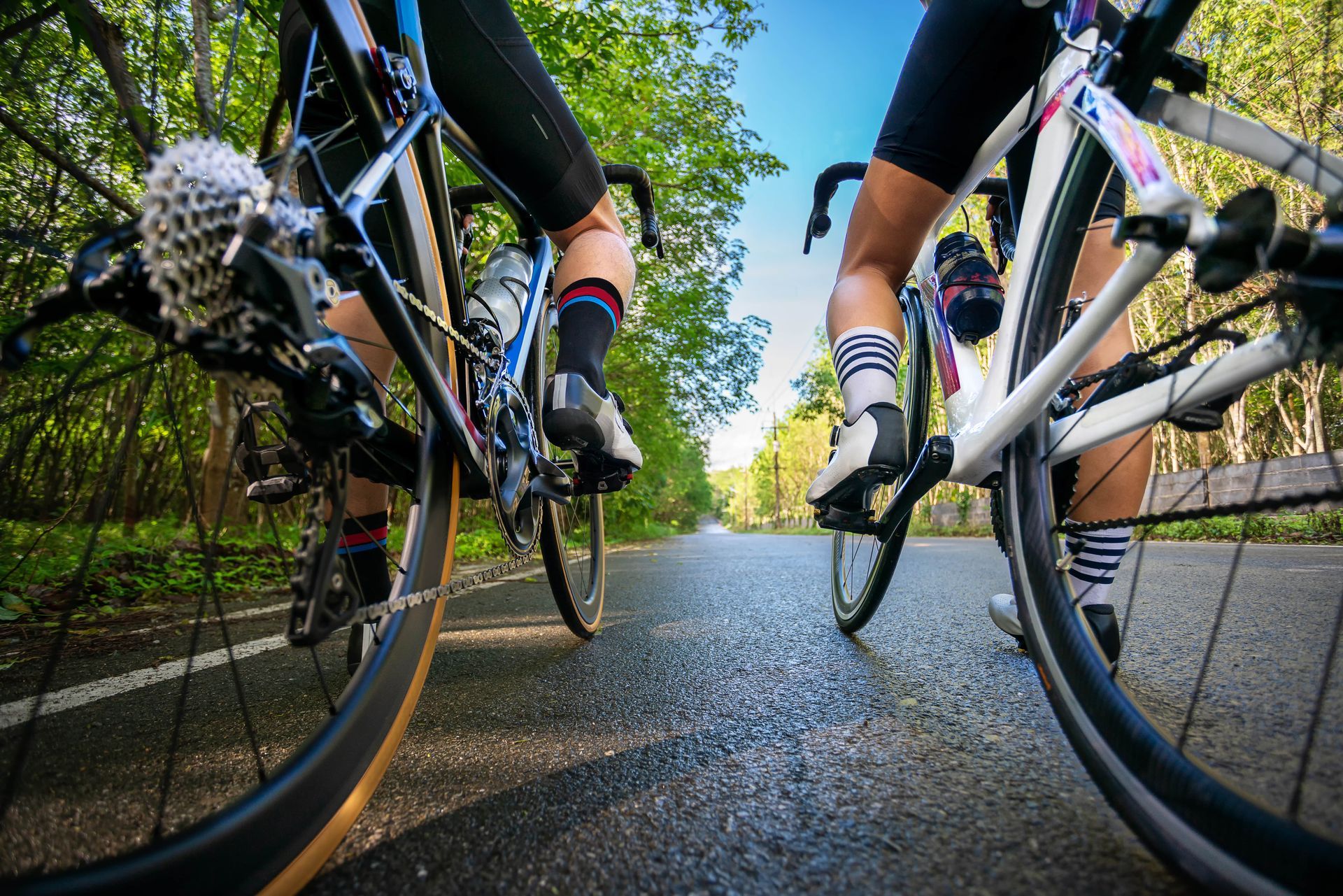 close up of two people riding bikes on paved road