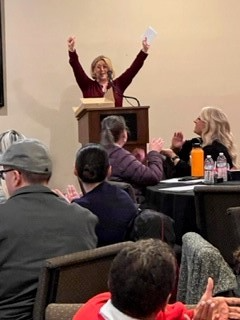 A woman is standing at a podium giving a speech to a group of people.