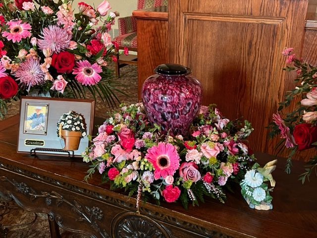 A table with a vase of flowers and a picture on it