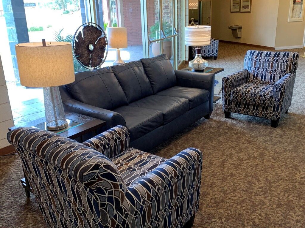 A living room with a couch , chairs , lamps and a fan.