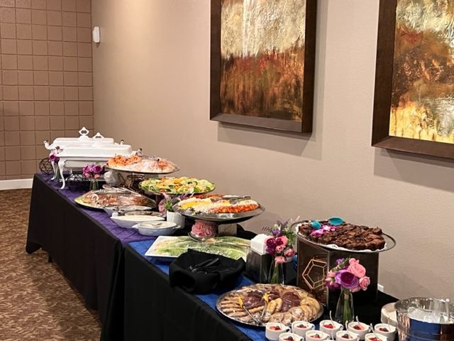 A buffet table filled with food and drinks in a room with paintings on the wall.