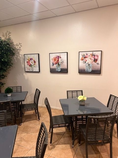 A dining room with tables and chairs and paintings on the wall