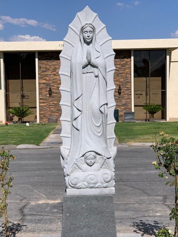 A statue of the virgin mary is in front of a building
