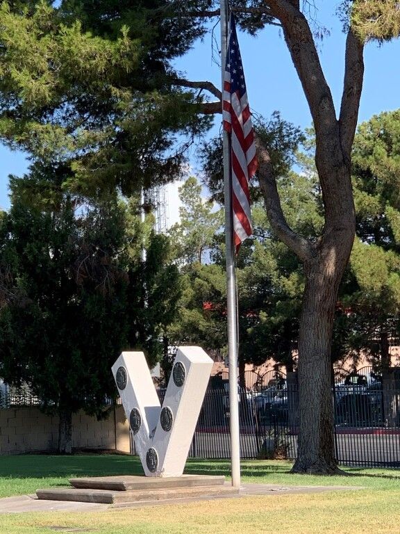 An american flag is flying in front of a statue of the letter v