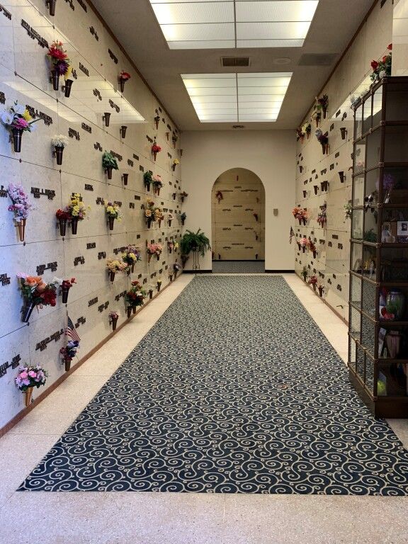 A hallway in a cemetery with flowers on the wall