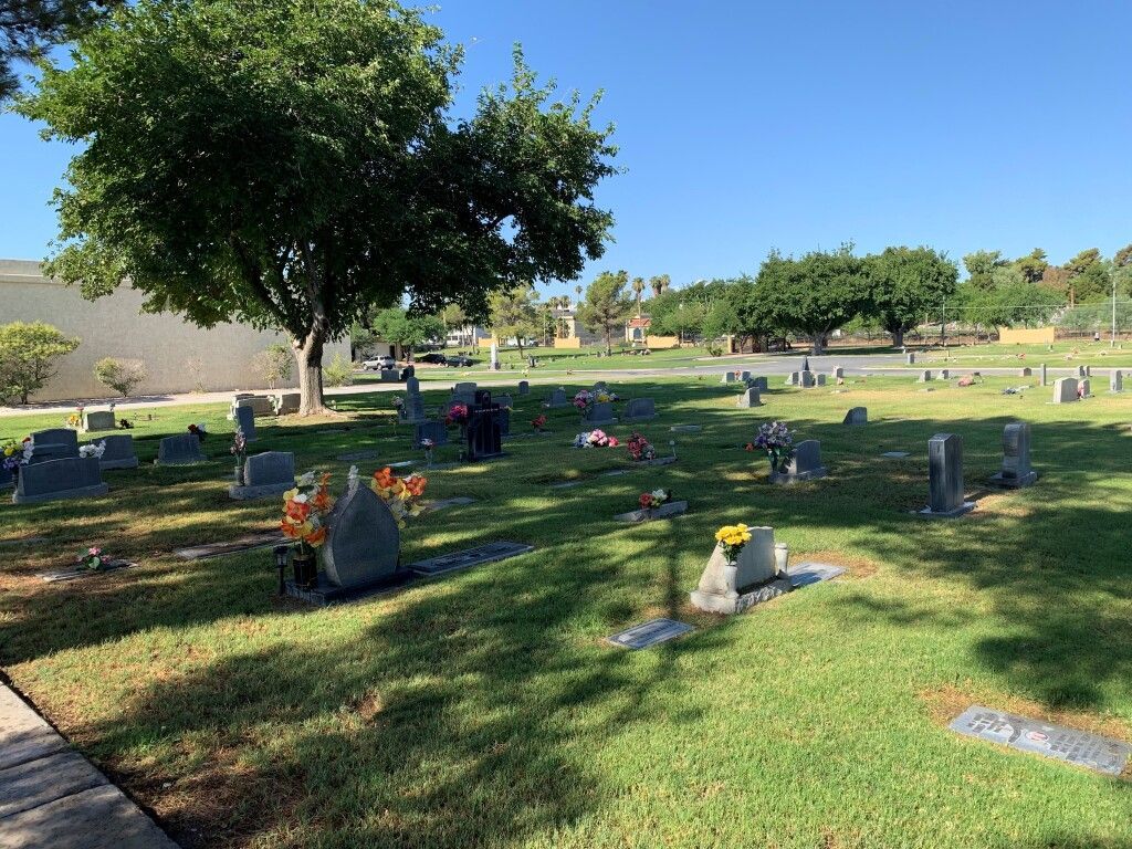 A cemetery filled with graves and flowers on a sunny day.