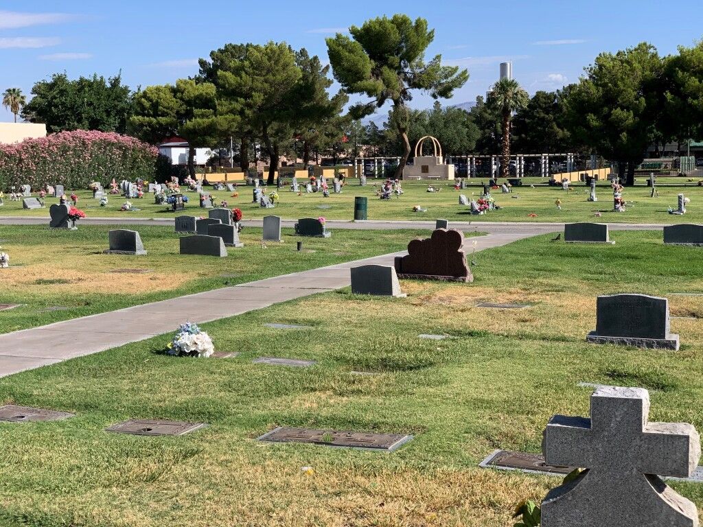 A cemetery with a lot of graves and a cross in the middle.