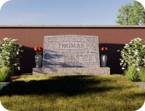 A gravestone in a cemetery with flowers and a brick wall.