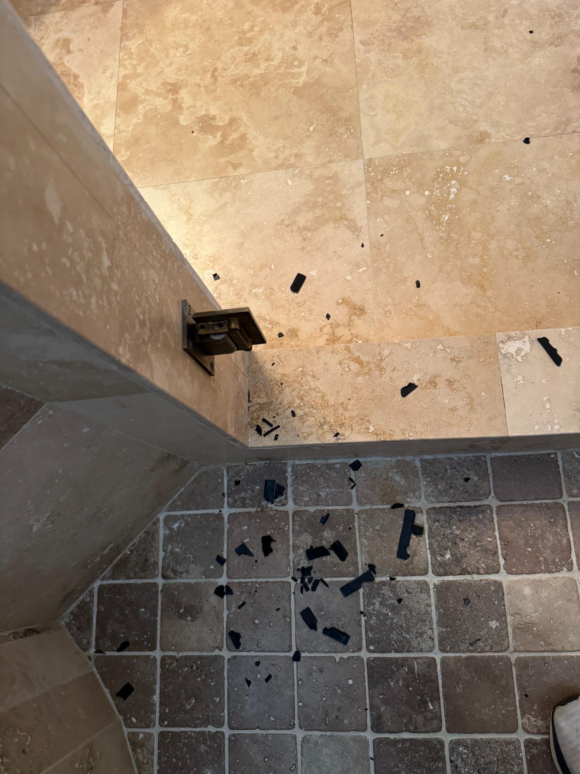 A damaged metal bracket with debris on a tile floor next to a pillar.