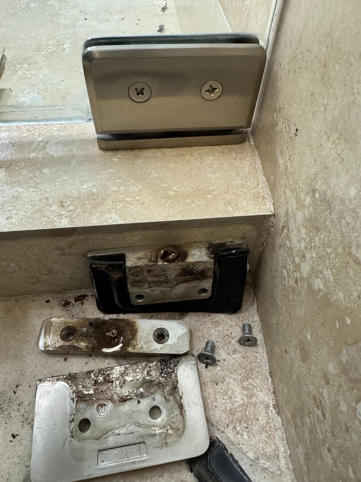 Glass door hardware, new and corroded, on stone steps.