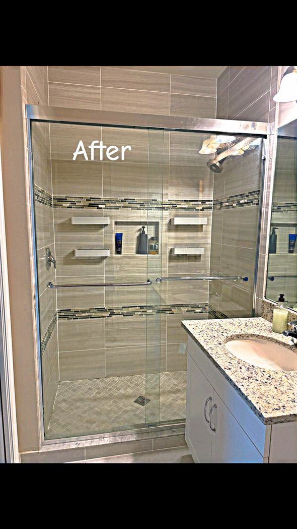 Modern shower with glass doors, tiled walls, and built-in shelves. Granite countertop.