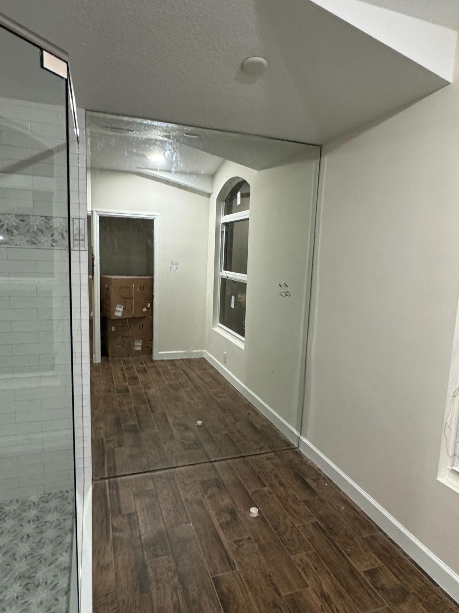 Hallway with wood-look floor, arched window, and large mirror on the ceiling.