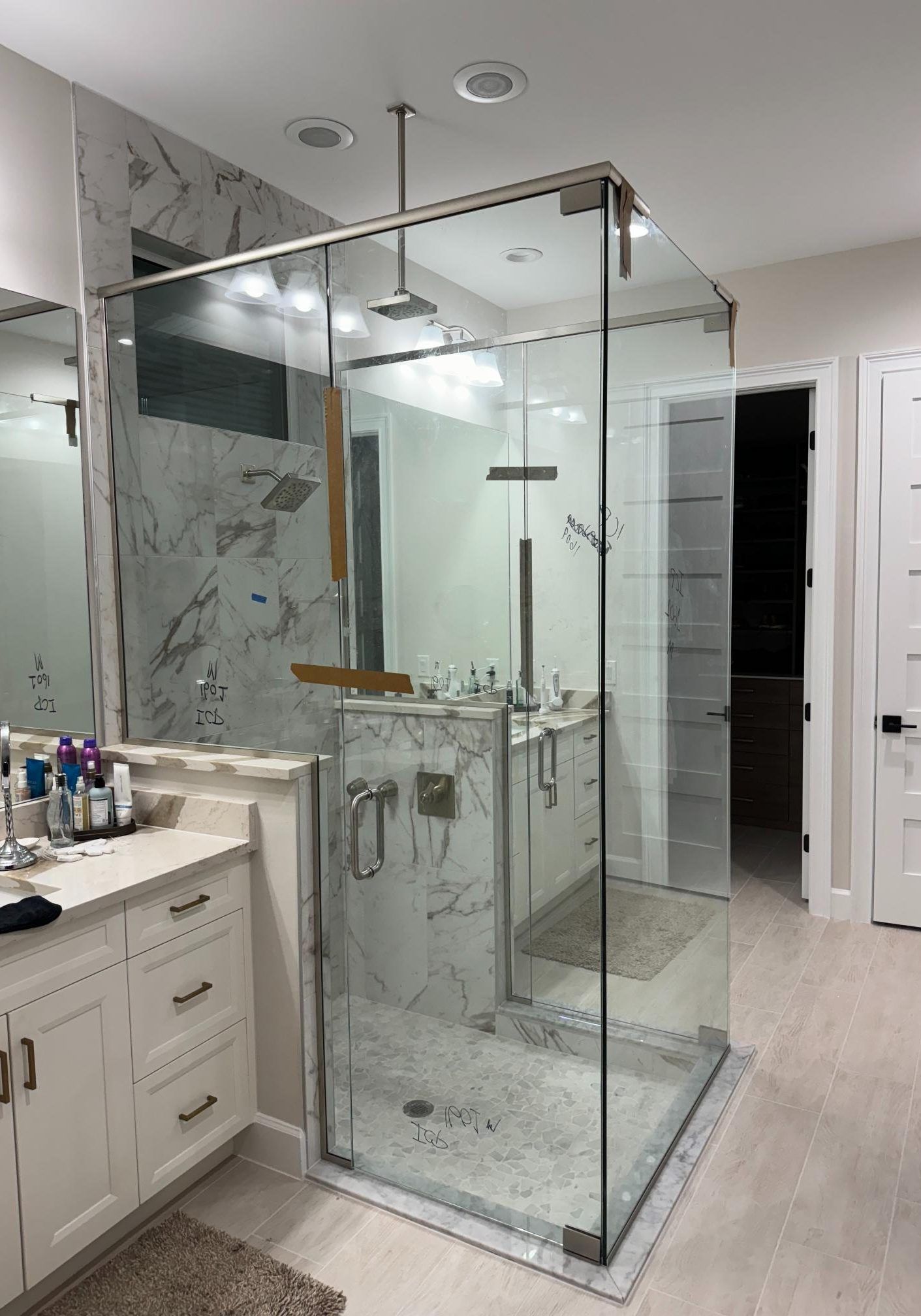 Modern bathroom with glass shower enclosure, vanity, and light-colored tile floor.