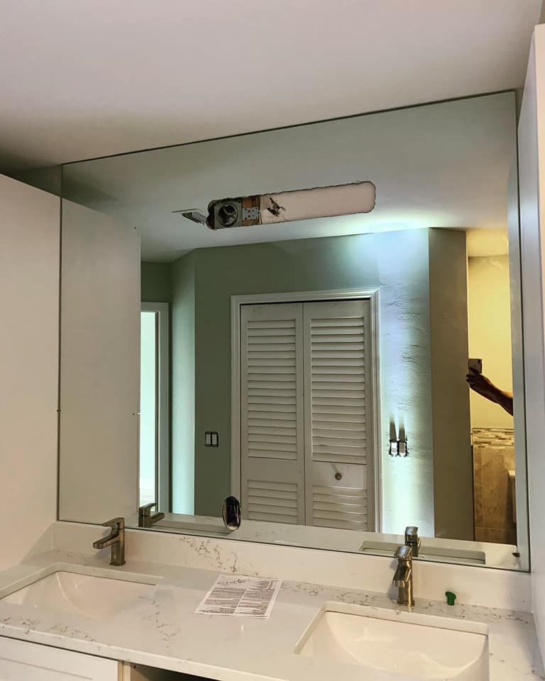 Bathroom mirror above a double sink, reflecting a white door and green wall.