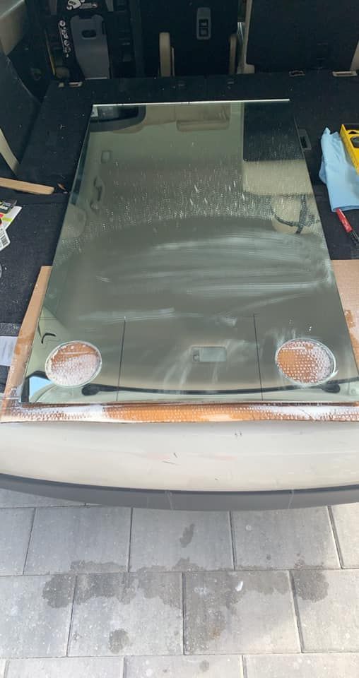 A large, rectangular piece of glass with two circular holes, lying in the open back of a vehicle.