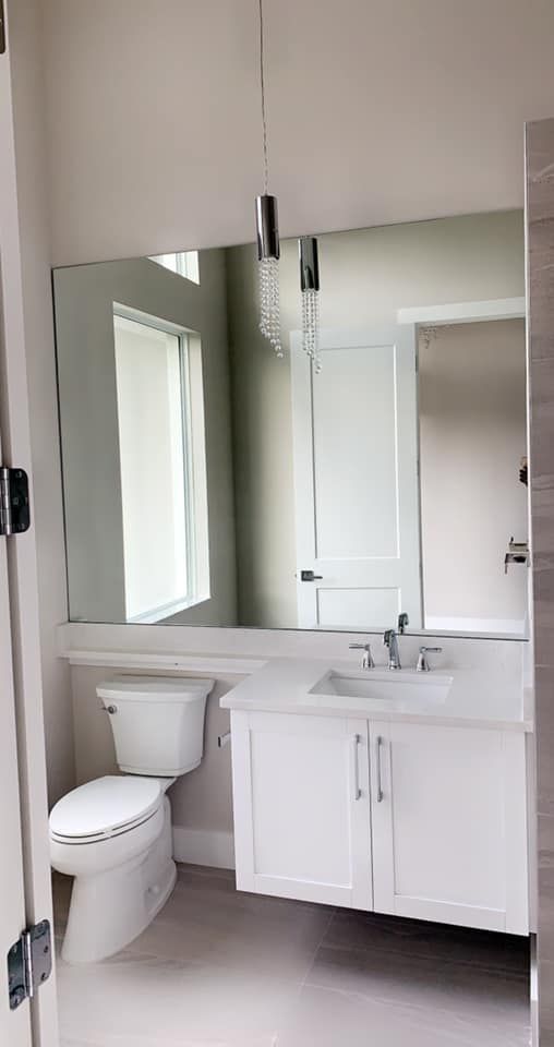 Bathroom with a white toilet, vanity, and large mirror.