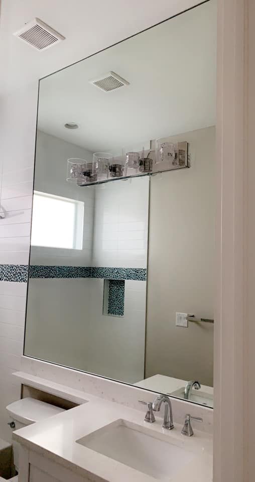 Bathroom with large wall mirror above a sink and light fixture.