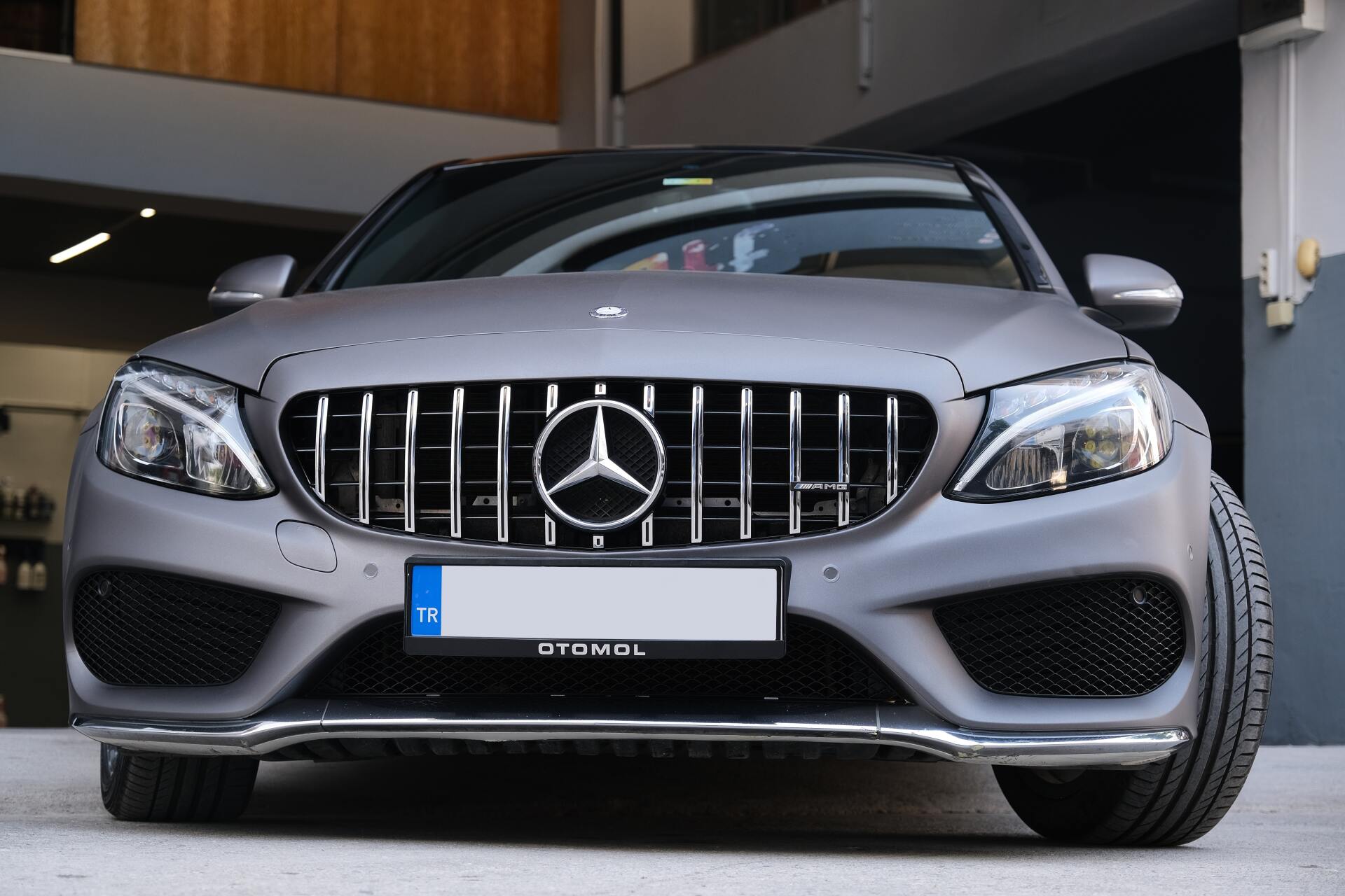 A person wearing black gloves is cleaning a black car with a blue cloth.