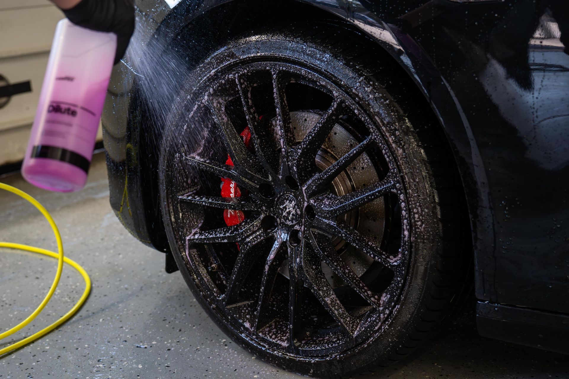 A person is cleaning a car wheel with a spray bottle.