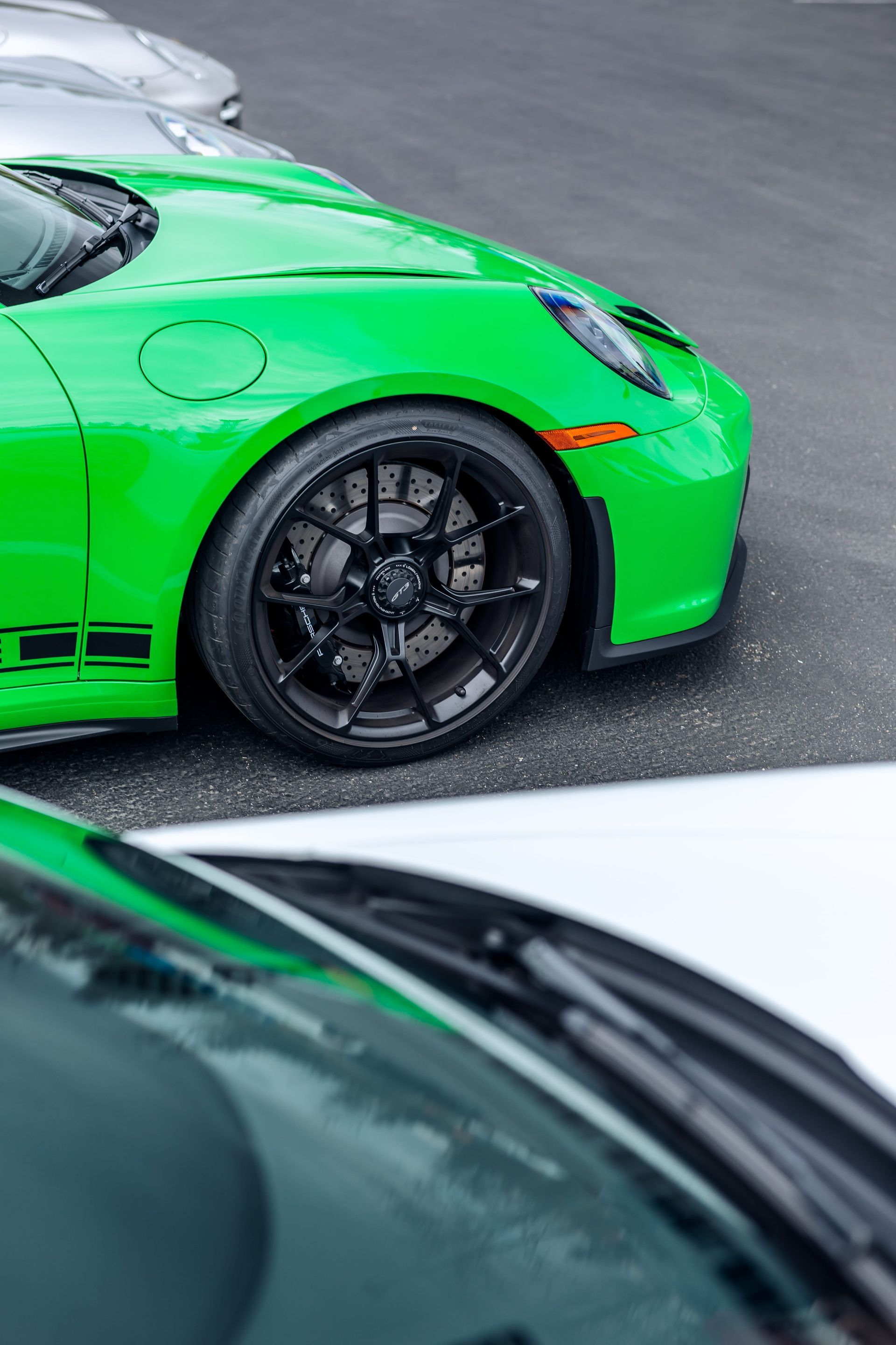 A green sports car is parked next to a white sports car.