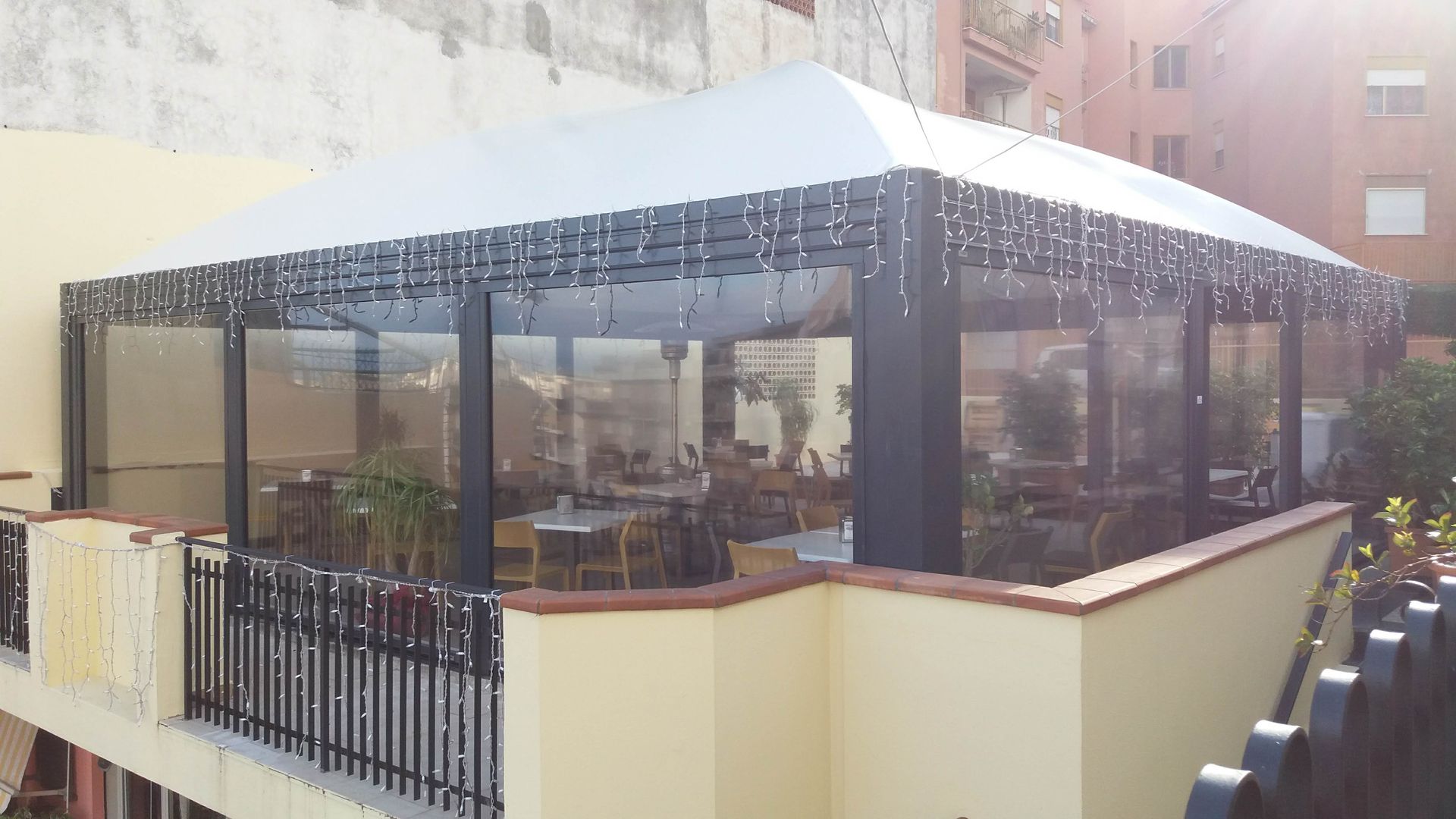 Un balcone con tavoli e sedie sotto una tettoia