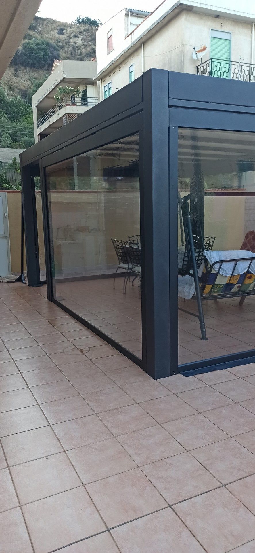 Un patio con pergolato, tavolo e sedie.