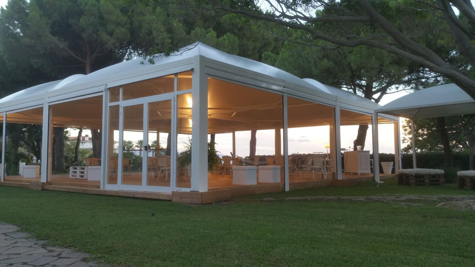 Una grande tenda bianca è posizionata in mezzo a un rigoglioso campo verde.