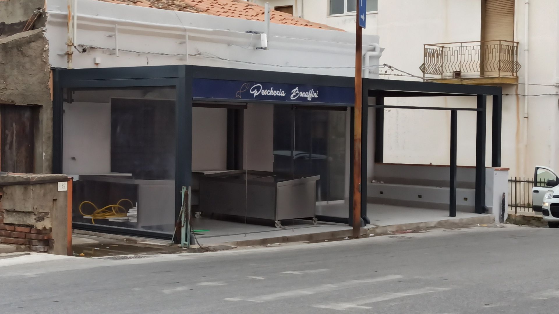 Un'auto bianca è parcheggiata sul ciglio della strada di fronte a un edificio.