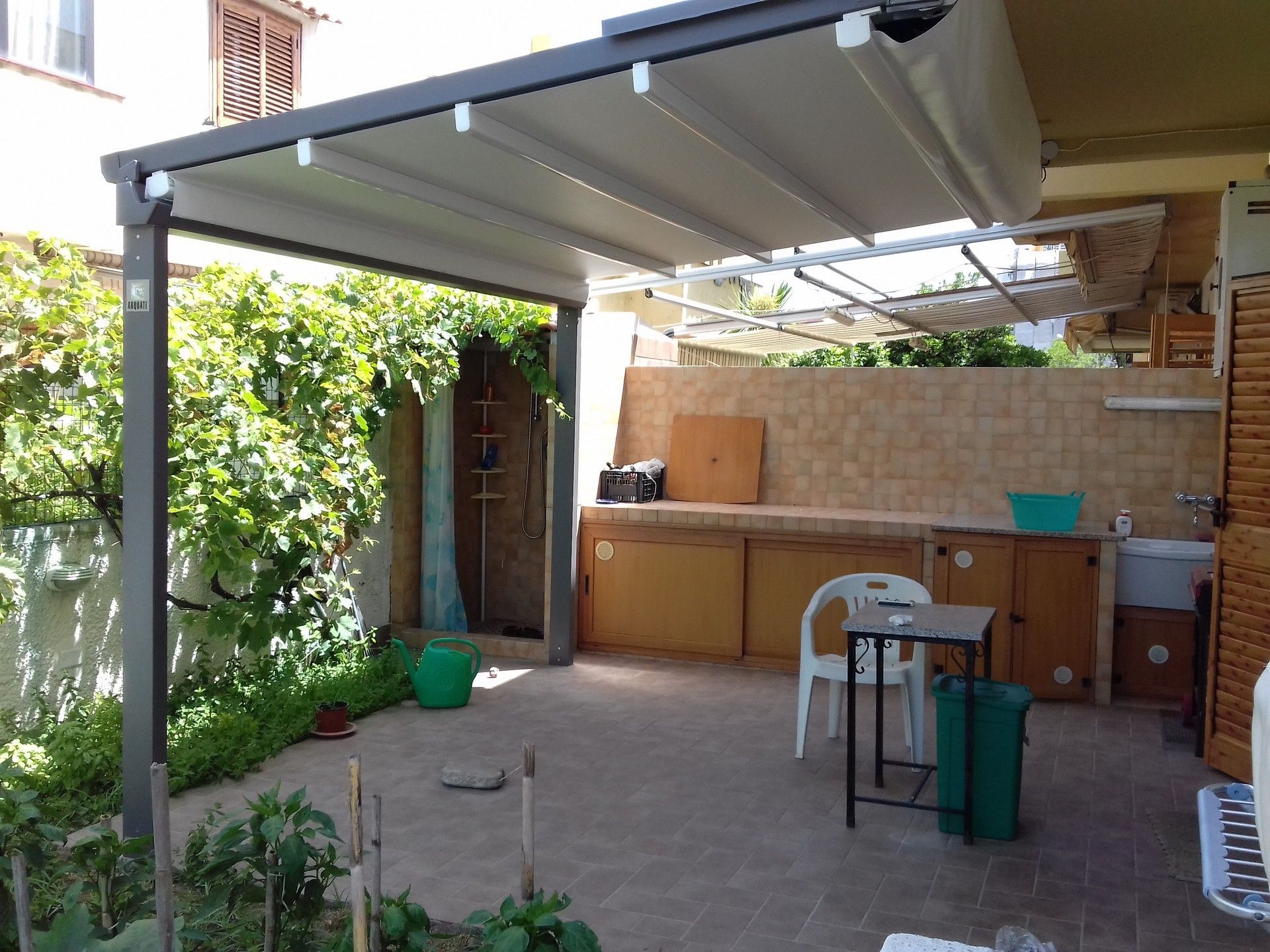 Un patio con tavolo e sedie sotto una tettoia