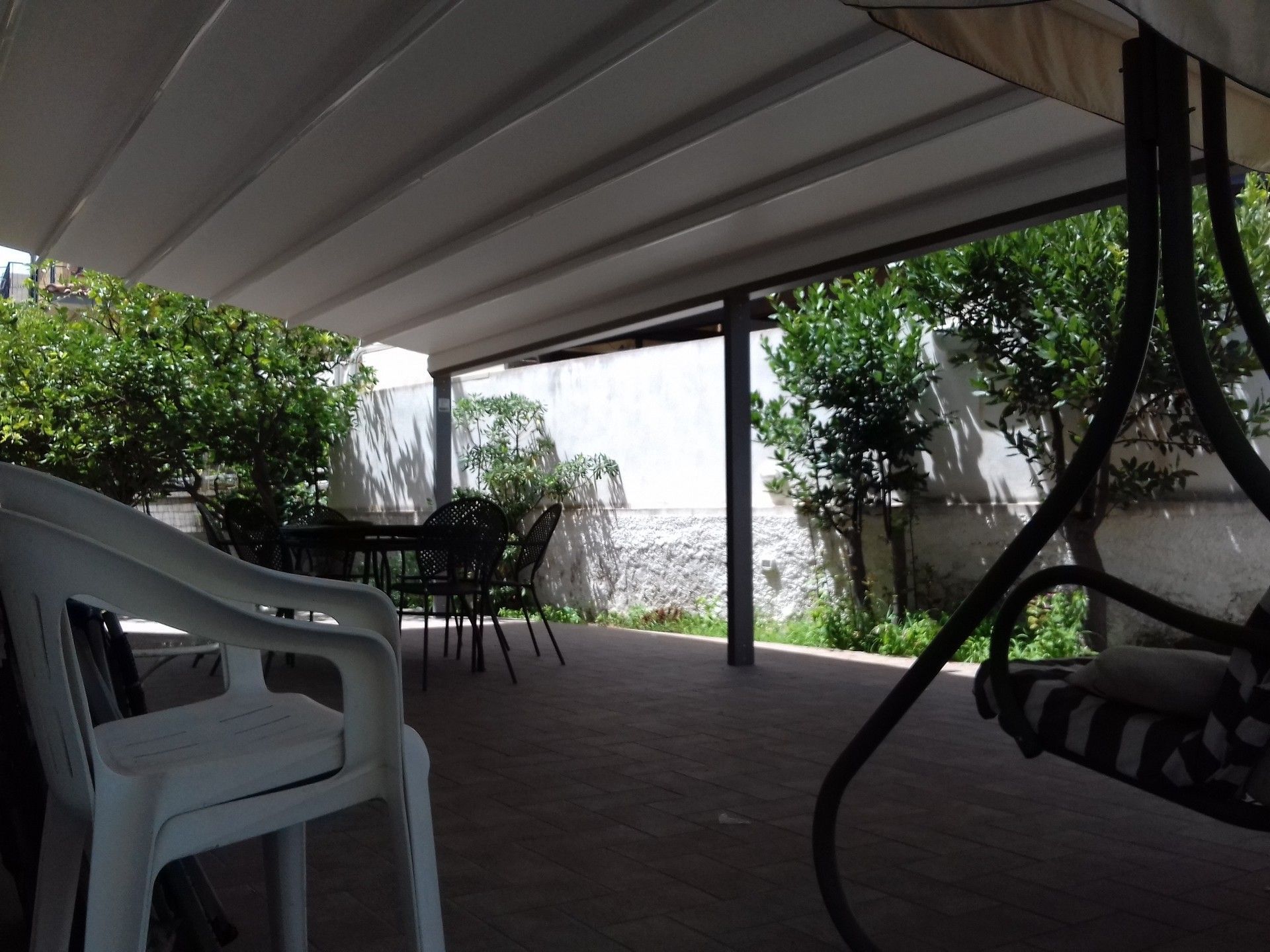 Un patio con sedie e un'altalena sotto una tettoia