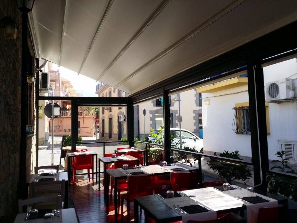 Un ristorante con tavoli e sedie sotto una tettoia