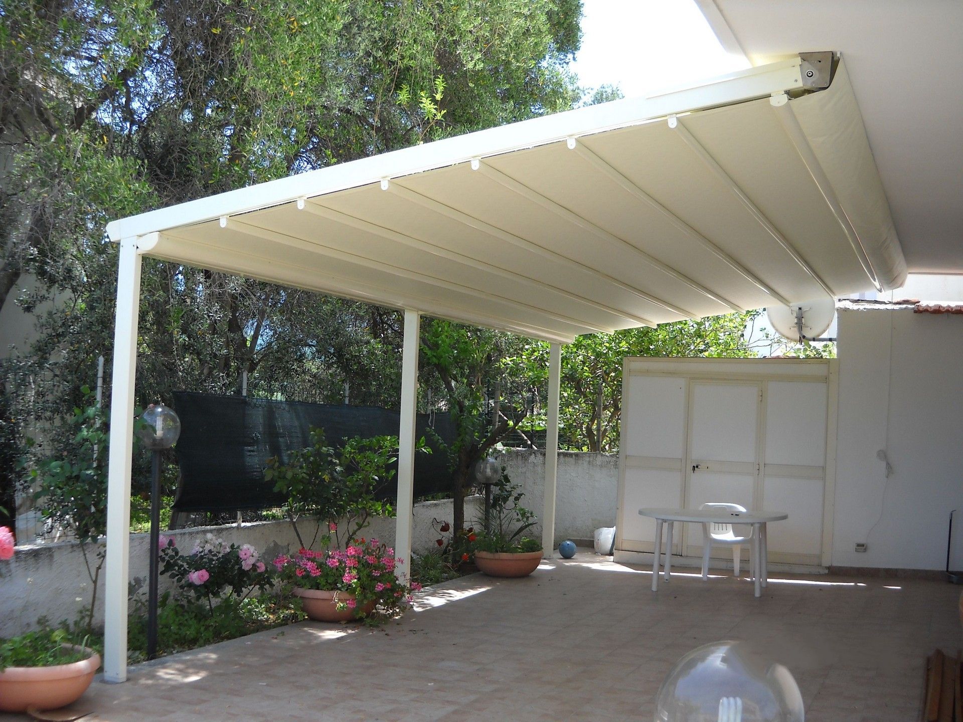 Una tettoia bianca sopra un patio con tavolo e sedie
