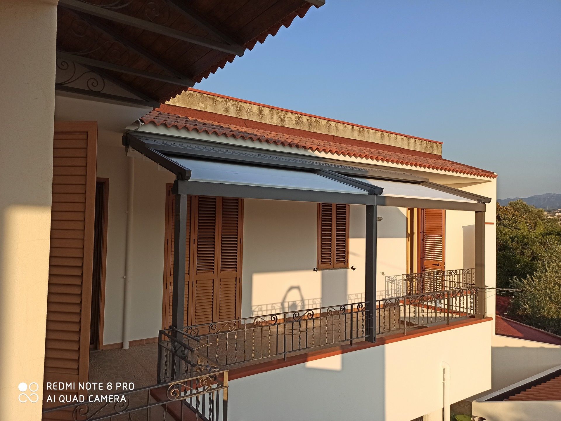 Una casa bianca con un balcone e un tetto di tegole rosse