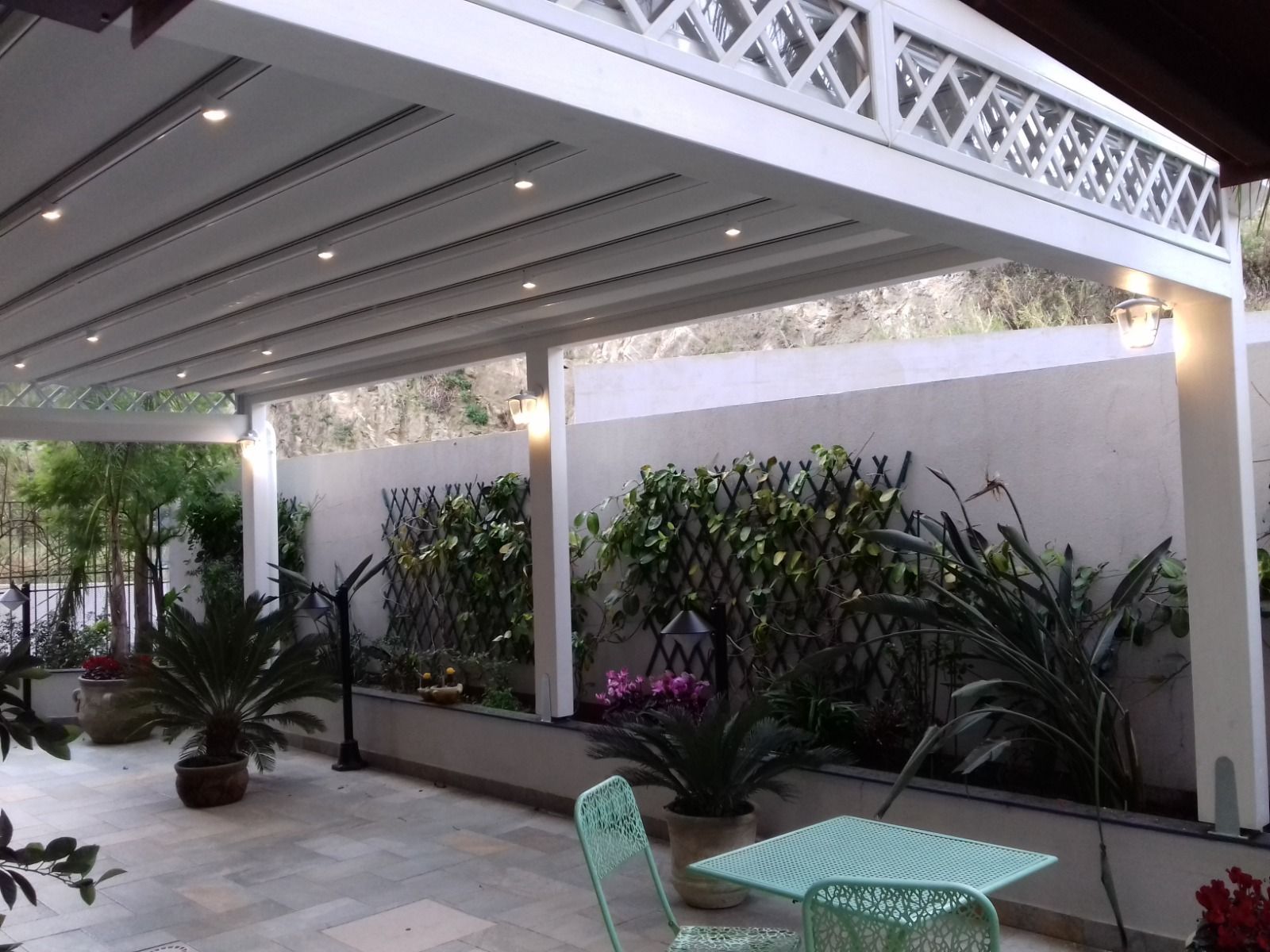 Un patio con tavolo e sedie sotto un pergolato