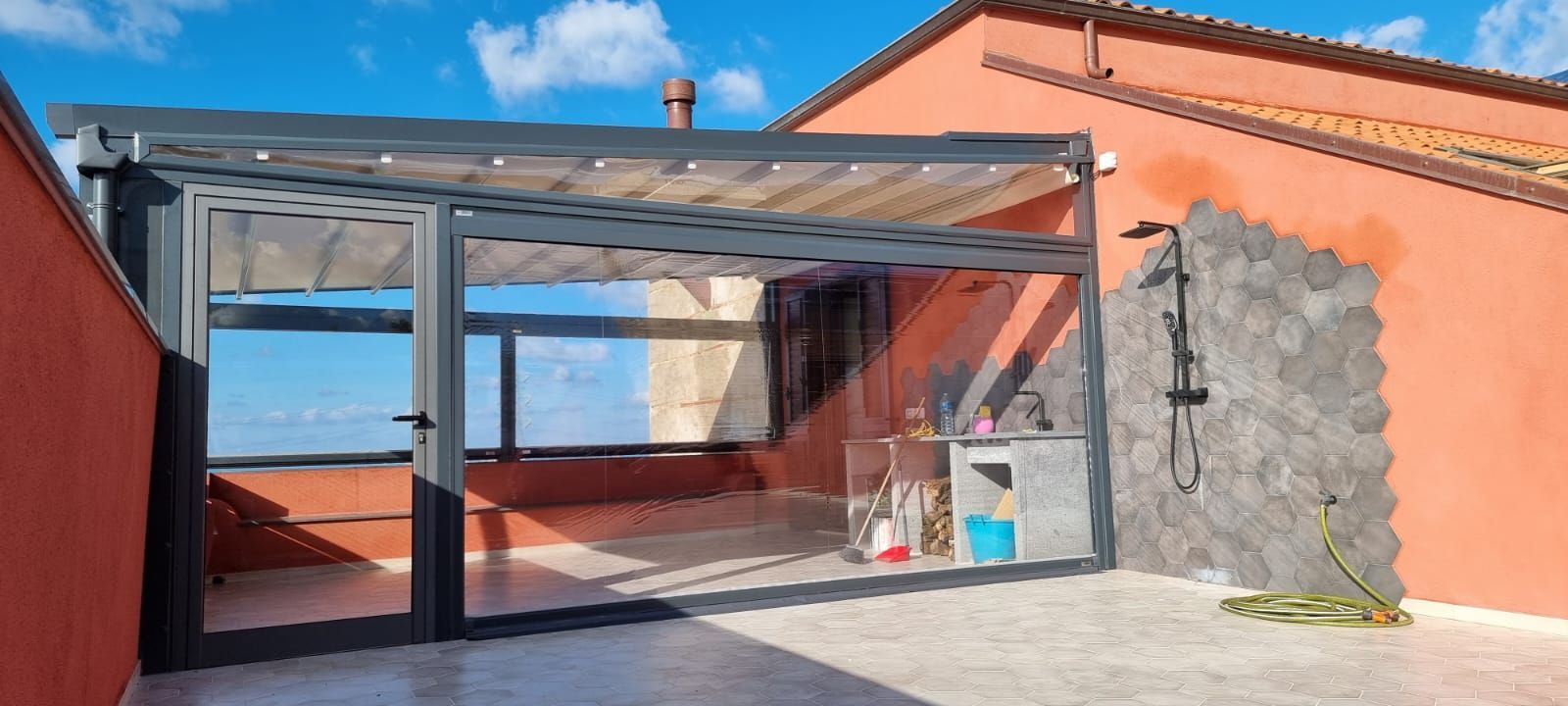Un patio con pergolato e doccia sul lato di un edificio.