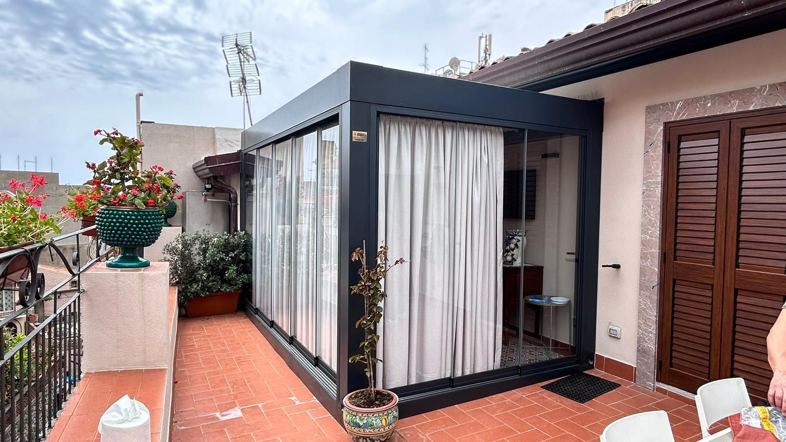 Una persona è in piedi su un balcone accanto a un edificio con una porta scorrevole in vetro.