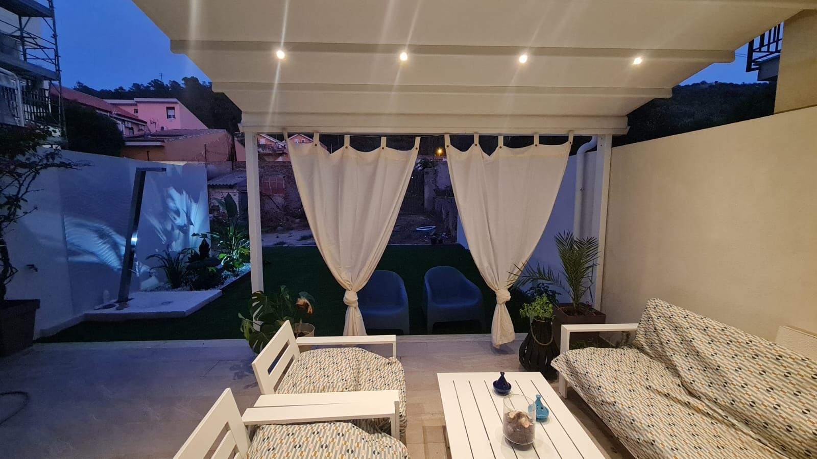 Un patio con un divano, sedie e un tavolo sotto una tettoia.